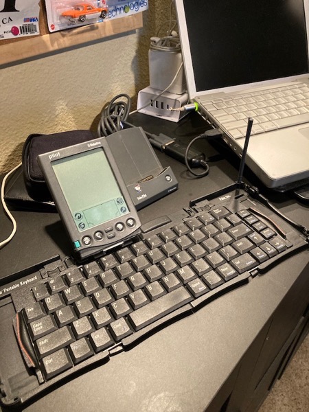 Palm Pilot connected to Palm Folding Keyboard sitting next to 12-inch Apple Powerbook